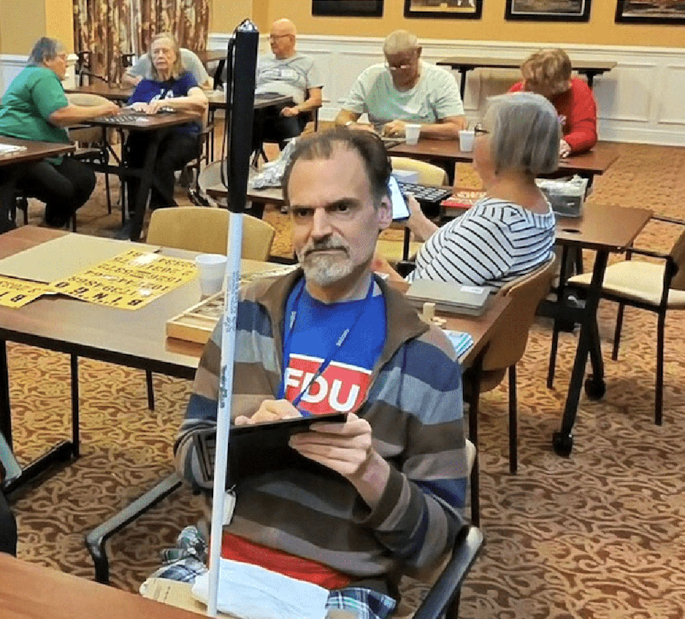 Senior with low vision uses adaptive bingo equipment during a Game Day event in Sun City Center.