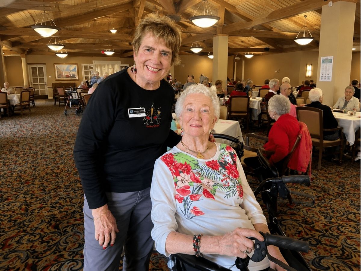 Seniors in Service Ambassador Anne Kramer visits with a resident at an assisted living community after volunteering as a bingo caller.