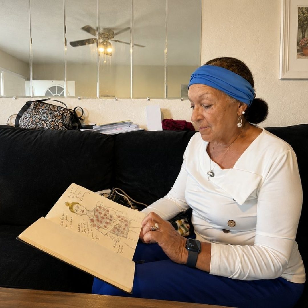 Senior Companion volunteer Carmen reviews sketches in her notebook during a home visit, using art to help seniors share and preserve meaningful memories.