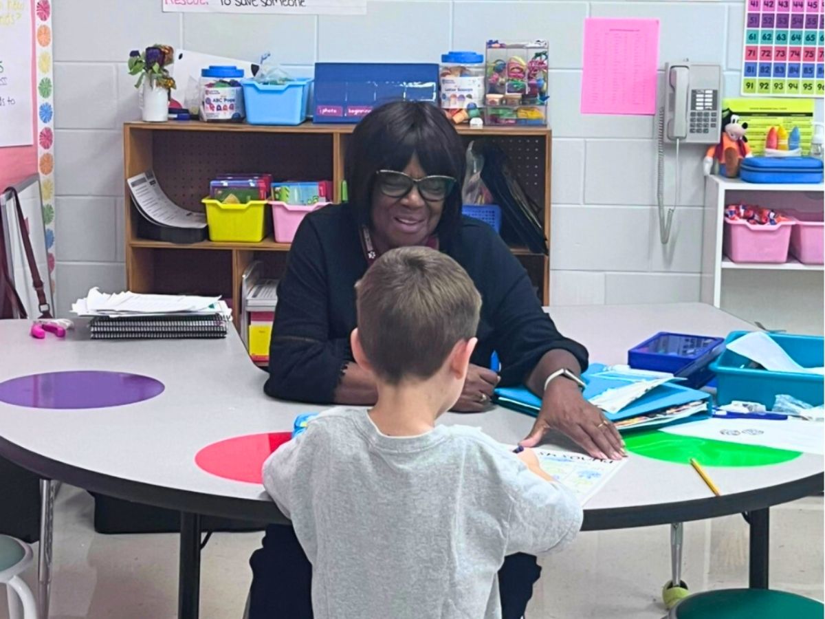 A Seniors in Service Classroom Grandparent volunteer helps an elementary school student build reading skills during a one-on-one literacy session.