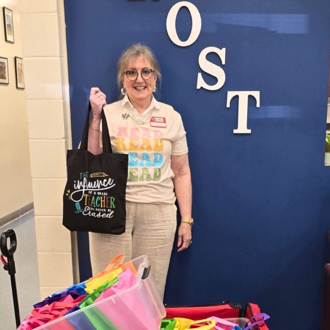Classroom Grandparent volunteer Angel stands at Frost Elementary School with reading materials and gifts for students she mentors through the Seniors in Service program.