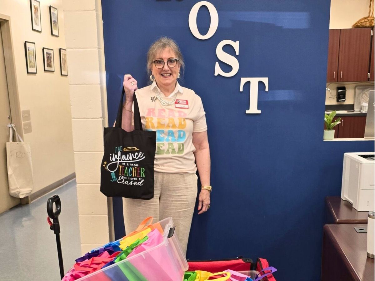 Classroom Grandparent volunteer Angel stands at Frost Elementary School with reading materials and gifts for students she mentors through the Seniors in Service program.