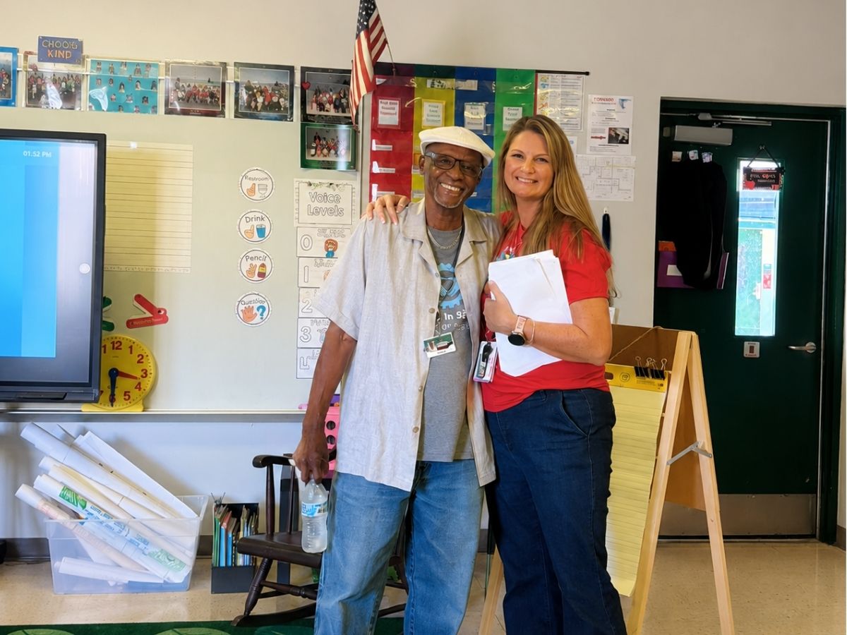 Classroom Grandparent volunteer reunites with an elementary school teacher during an open house event at a Title I school.