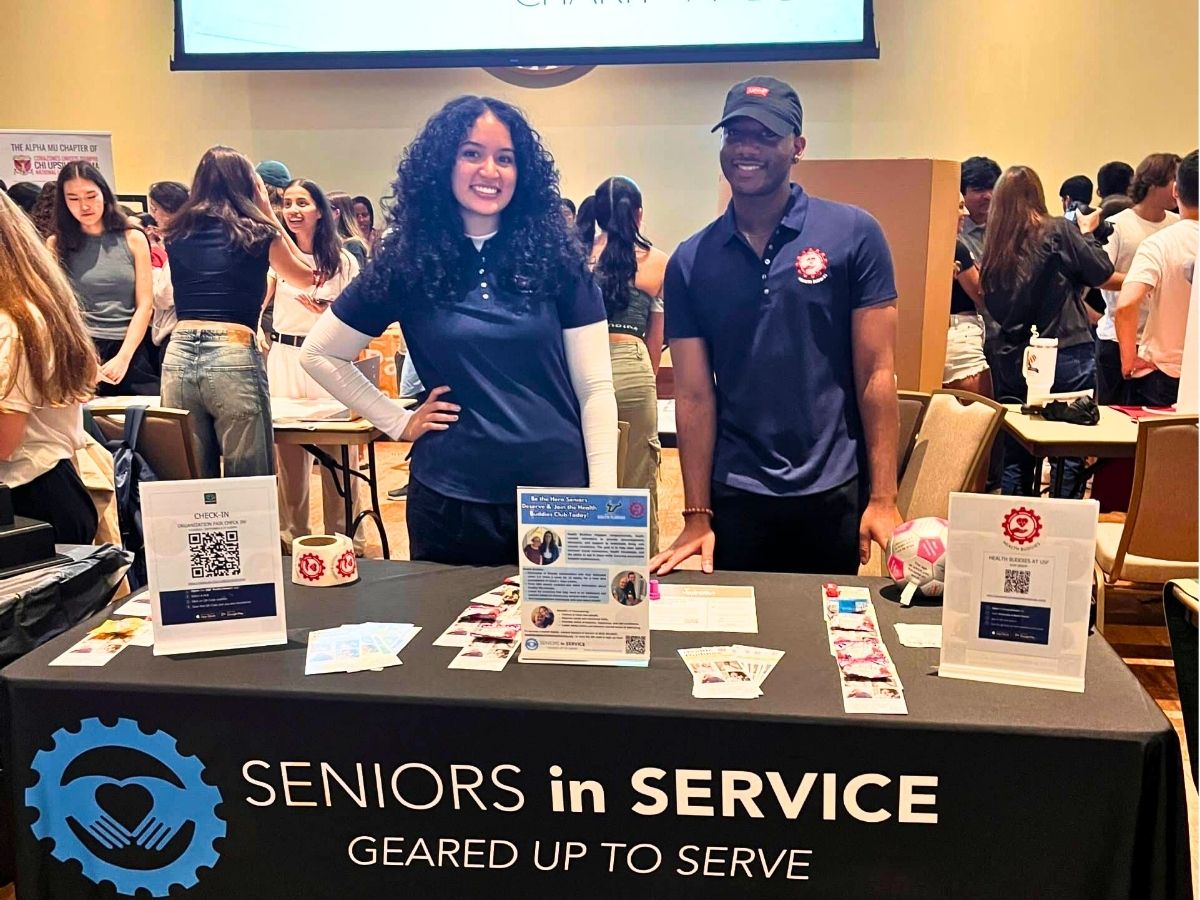 Health Buddies student leaders recruit volunteers at a college campus event promoting companionship and support for older adults.