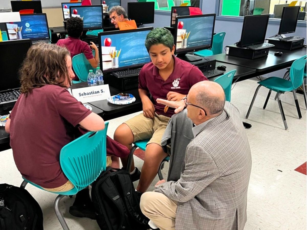 A JCC Mentor volunteer talks with middle school students during a small-group mentoring session at Ben Hill Middle School in Tampa.