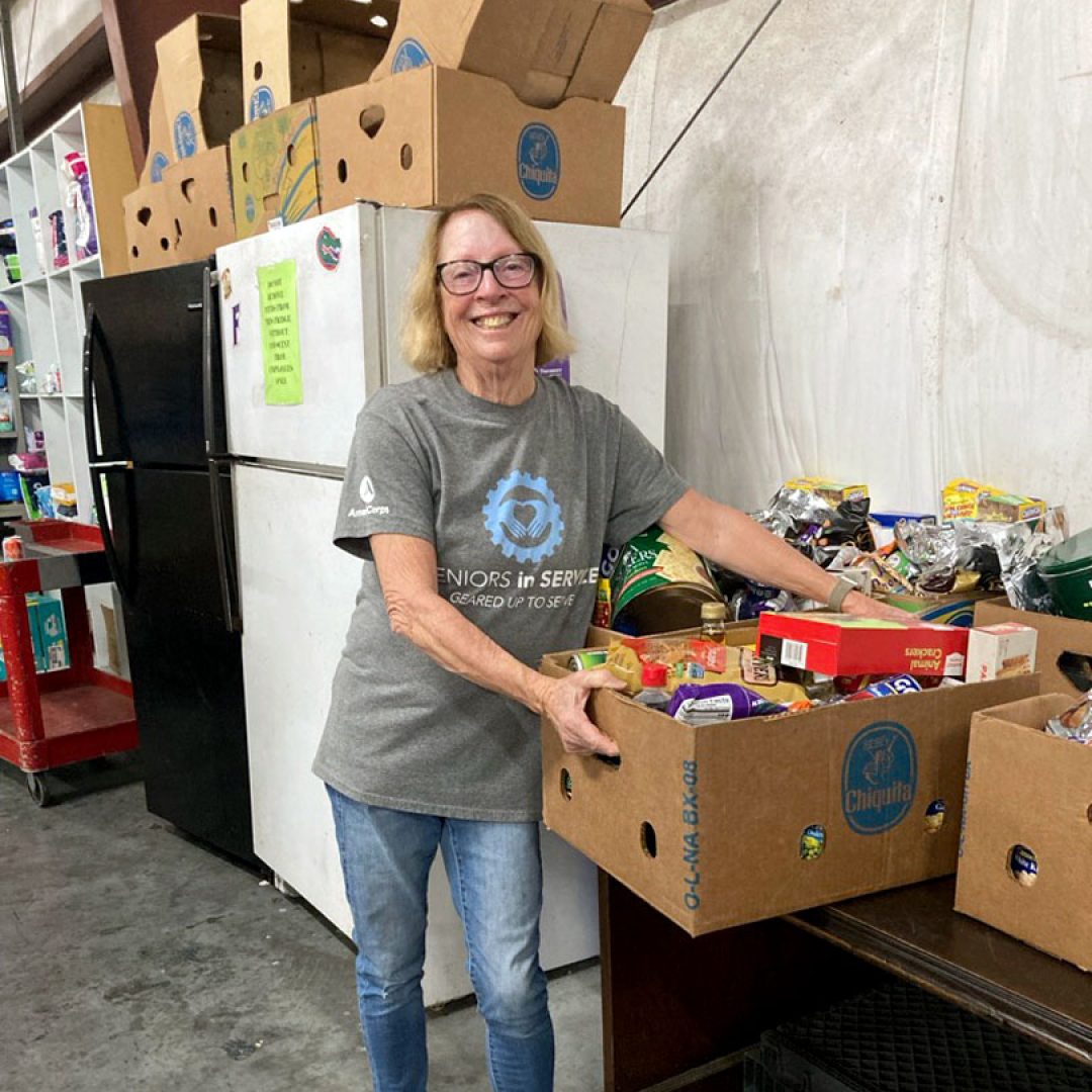 Seniors in Service volunteer Margie organizes donated food items at a community food pantry.