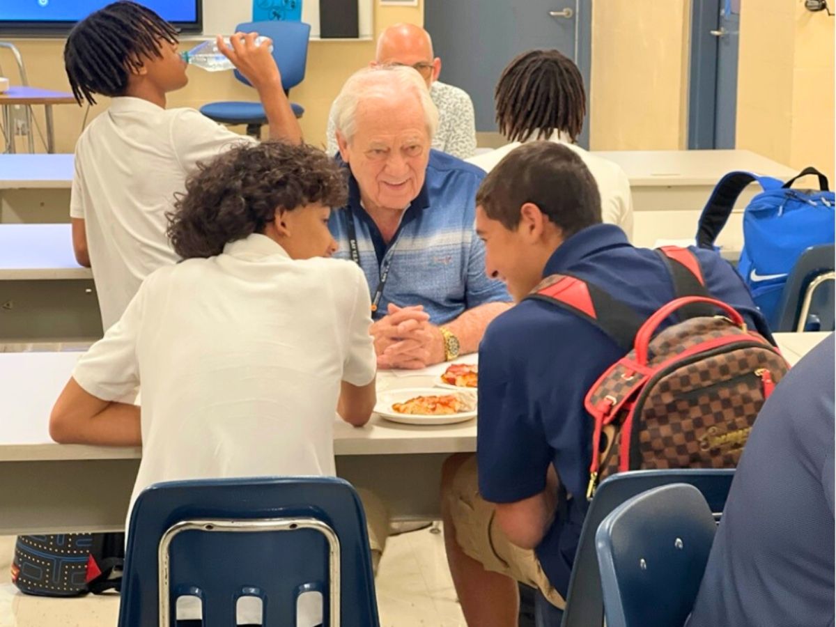 Volunteer mentor shares pizza and conversation with middle school students during a mentoring lunch at Ben Hill Middle School.