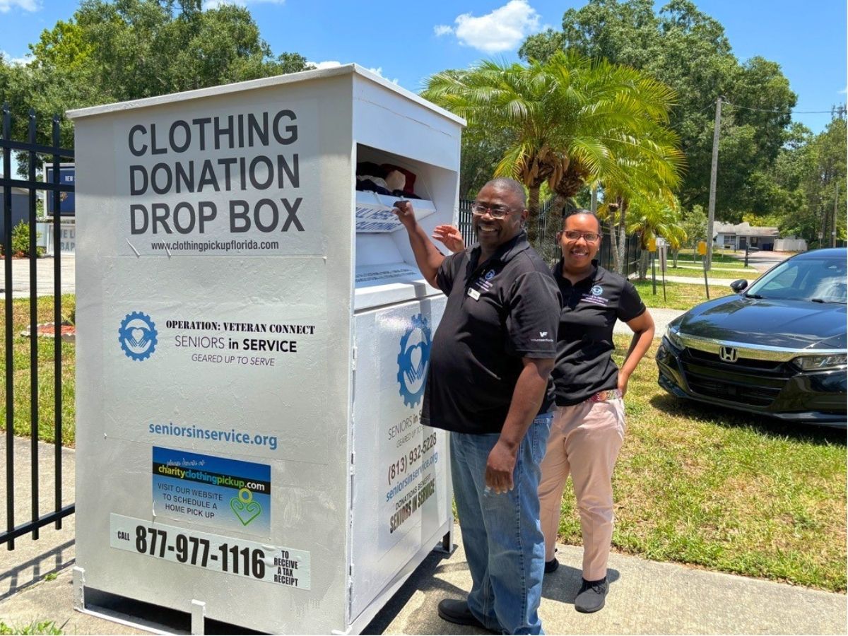 Operation: Veteran Connect volunteers stand beside a clothing donation drop box in Tampa that helps provide clothing and support for local veterans.