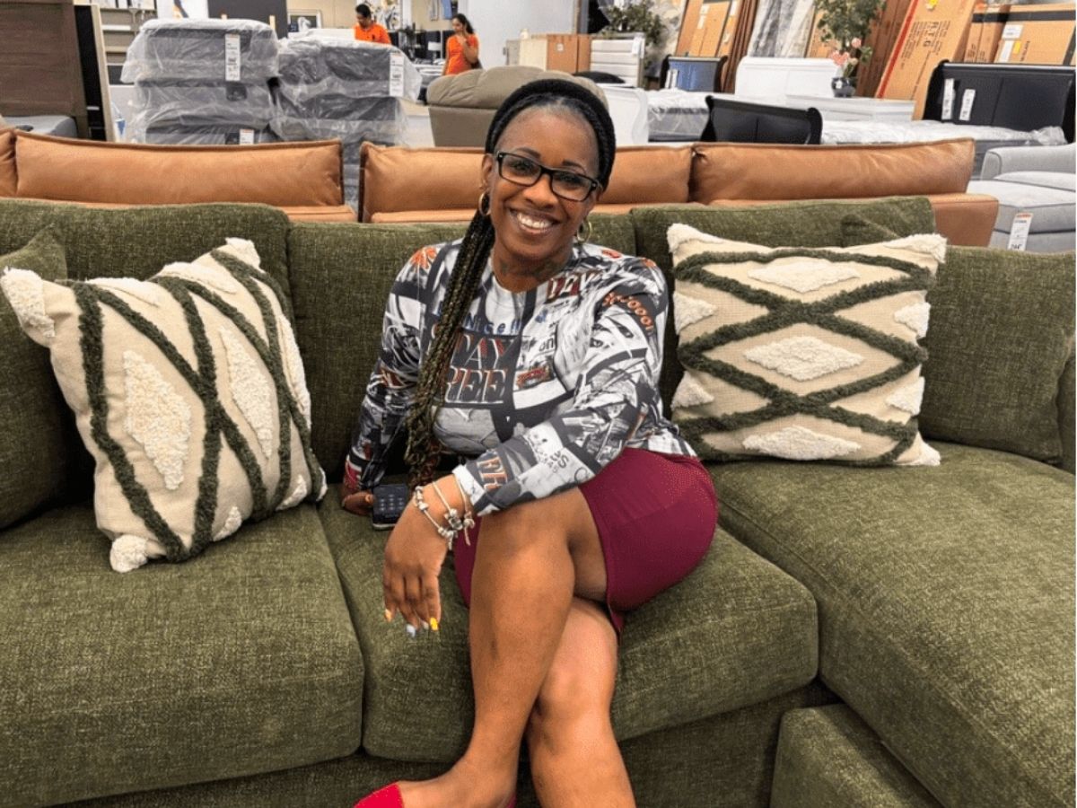 Army veteran and Operation: Veteran Connect volunteer Rosalind sits on a newly furnished sofa while helping veterans create comfortable, welcoming homes after housing instability and hurricane recovery.