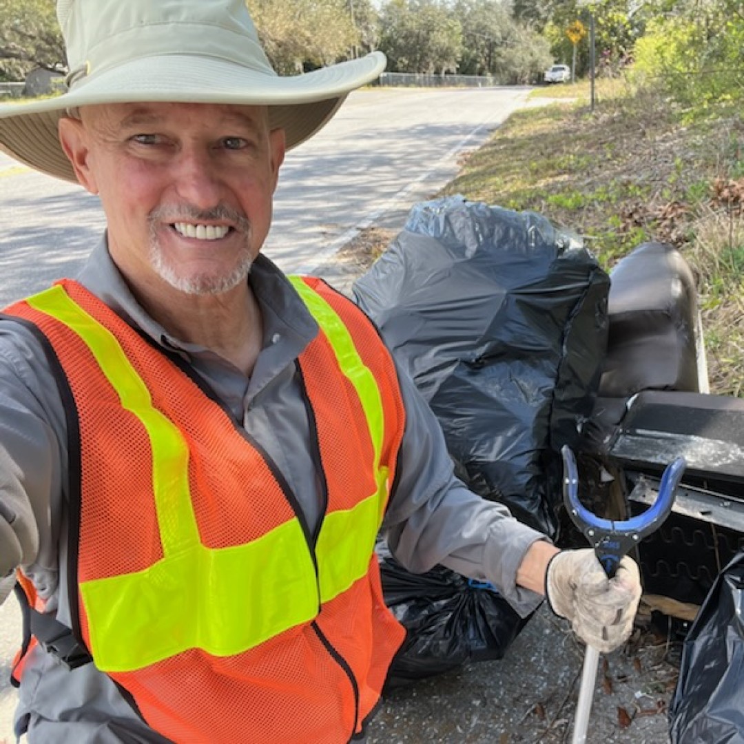 Volunteer collects roadside trash during a community cleanup in Pasco County to support local nonprofits.