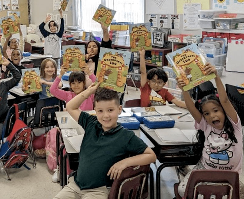 Elementary students at Mendenhall Elementary proudly hold Winter Activity Books provided through Seniors in Service's Readers in Motion program.