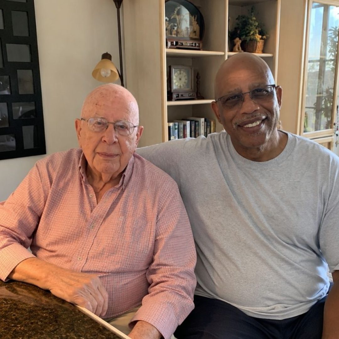 Senior Companion volunteer Herman Archie visits with client Murph in his home, providing companionship and support to help him remain independent.