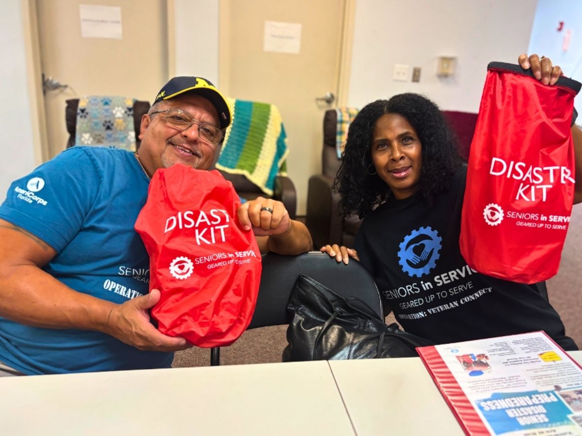 Seniors in Service volunteers hold emergency disaster preparedness kits during a Senior Disaster Support outreach event.