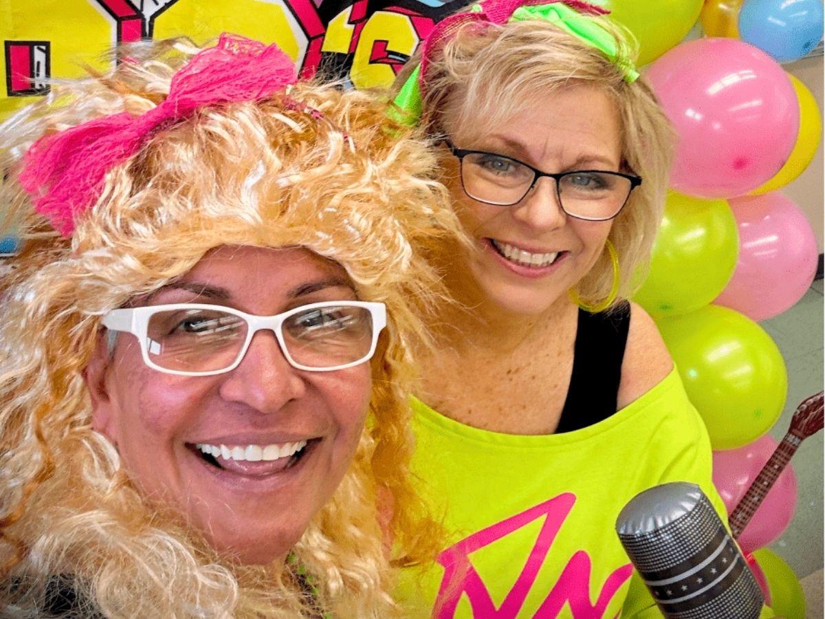 Two guests dressed in colorful 1980s costumes smile during Seniors in Service's 40th anniversary volunteer appreciation celebration.