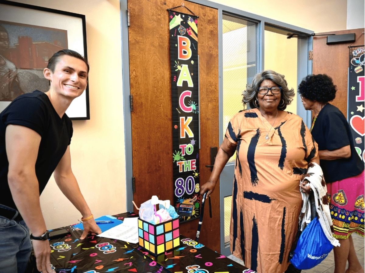 Guests arrive at the check-in table for Seniors in Service's 40th anniversary 1980s-themed volunteer appreciation celebration.