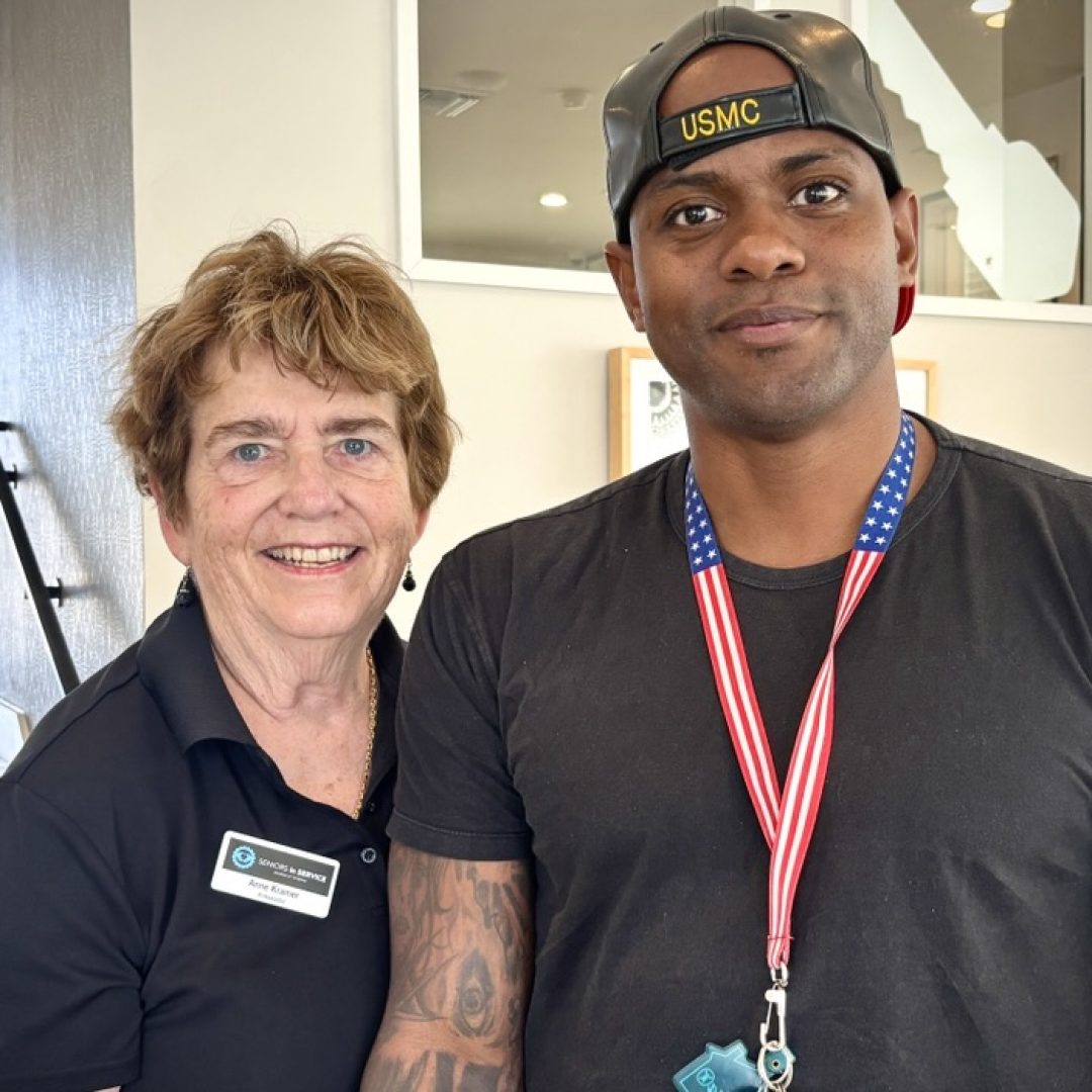Seniors in Service Ambassador Anne and Veteran at Community Event Seniors in Service Ambassador Anne smiling with a Veteran at a community event.