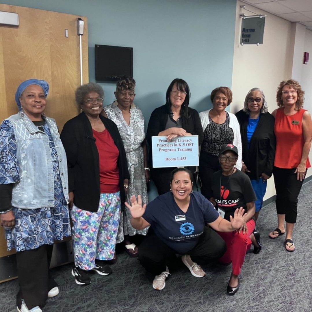 Classroom Grandparent volunteers smiling with Seniors in Service staff outside literacy practice training.