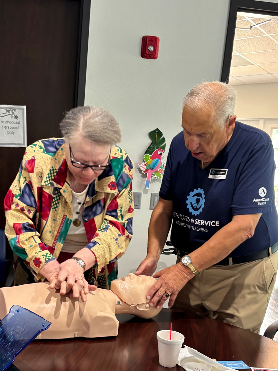 Two volunteers practicing CPR on a training mannequin during a hands-on emergency response training session.
