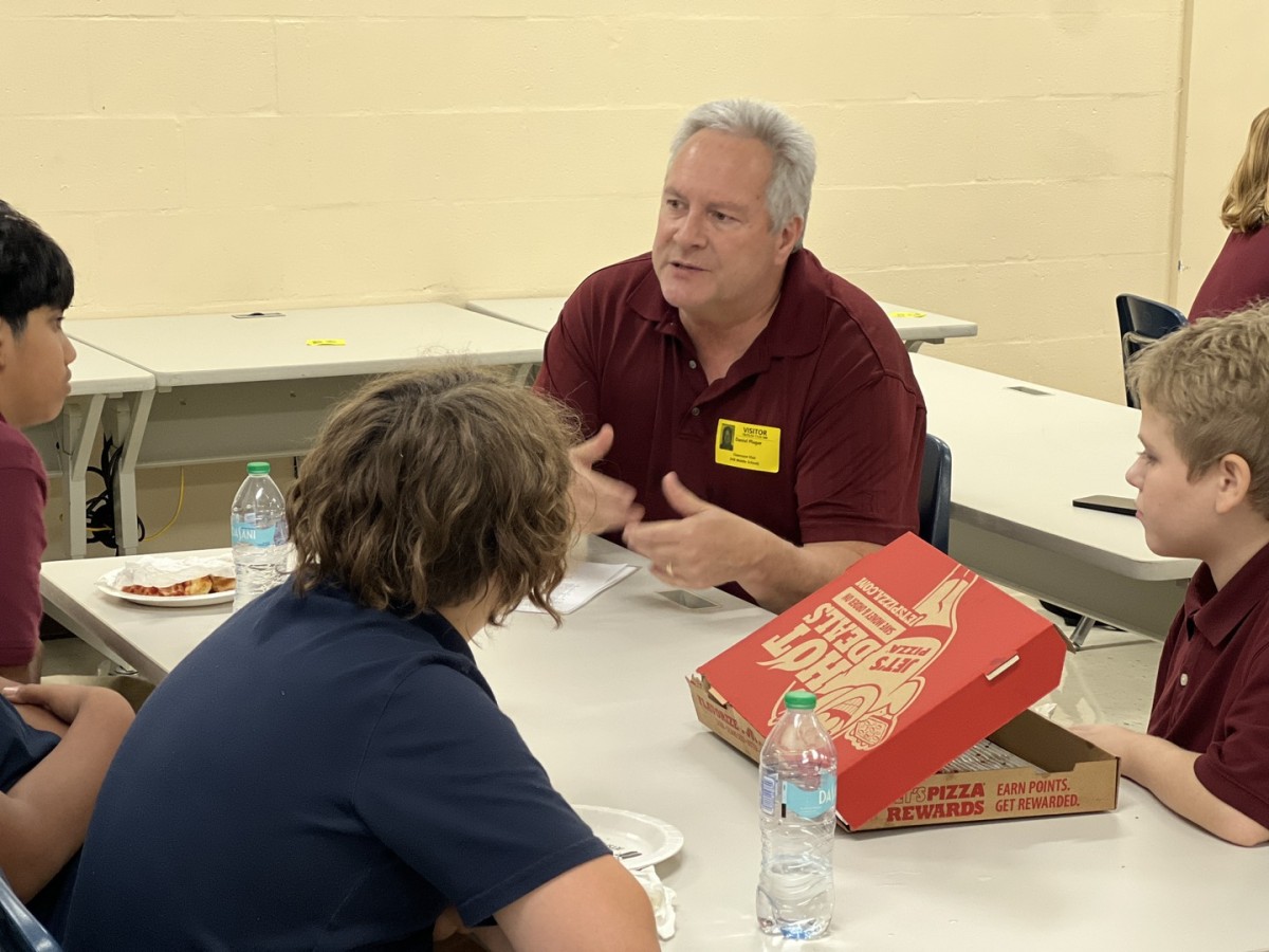 Volunteer mentor talks with middle school students during a mentoring session at Ben Hill Middle School.