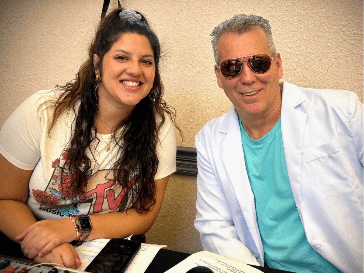 Two Seniors in Service staff members smile at the DJ and sound table during the organization's 40th anniversary 1980s-themed celebration.