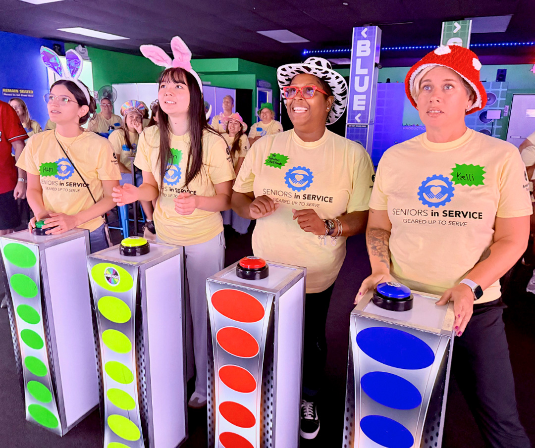 Seniors in Service staff members participate in a fast-paced game show challenge during a team-building event.