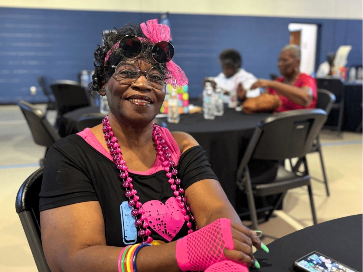 Volunteer dressed in colorful 1980s attire smiles during Seniors in Service's 40th anniversary volunteer appreciation celebration.