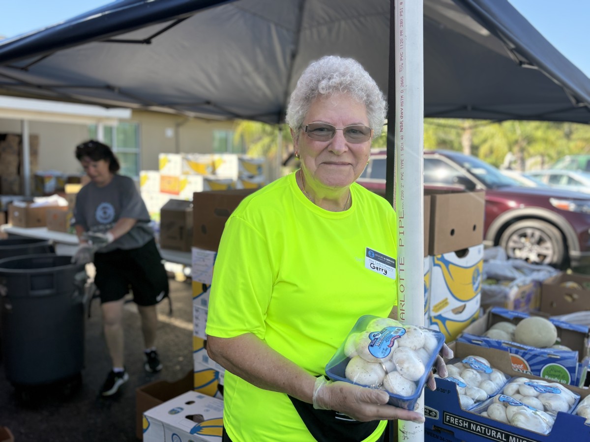 Seniors in Service volunteer shows fresh produce available at the Tampa Bay food pantry.