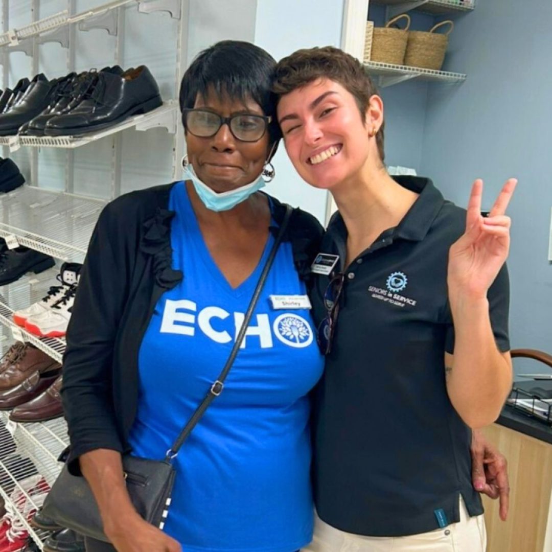 Shirley, a Seniors in Service volunteer, stands with a staff member at ECHO’s Resource Center in Brandon, helping families access clothing and essential resources.