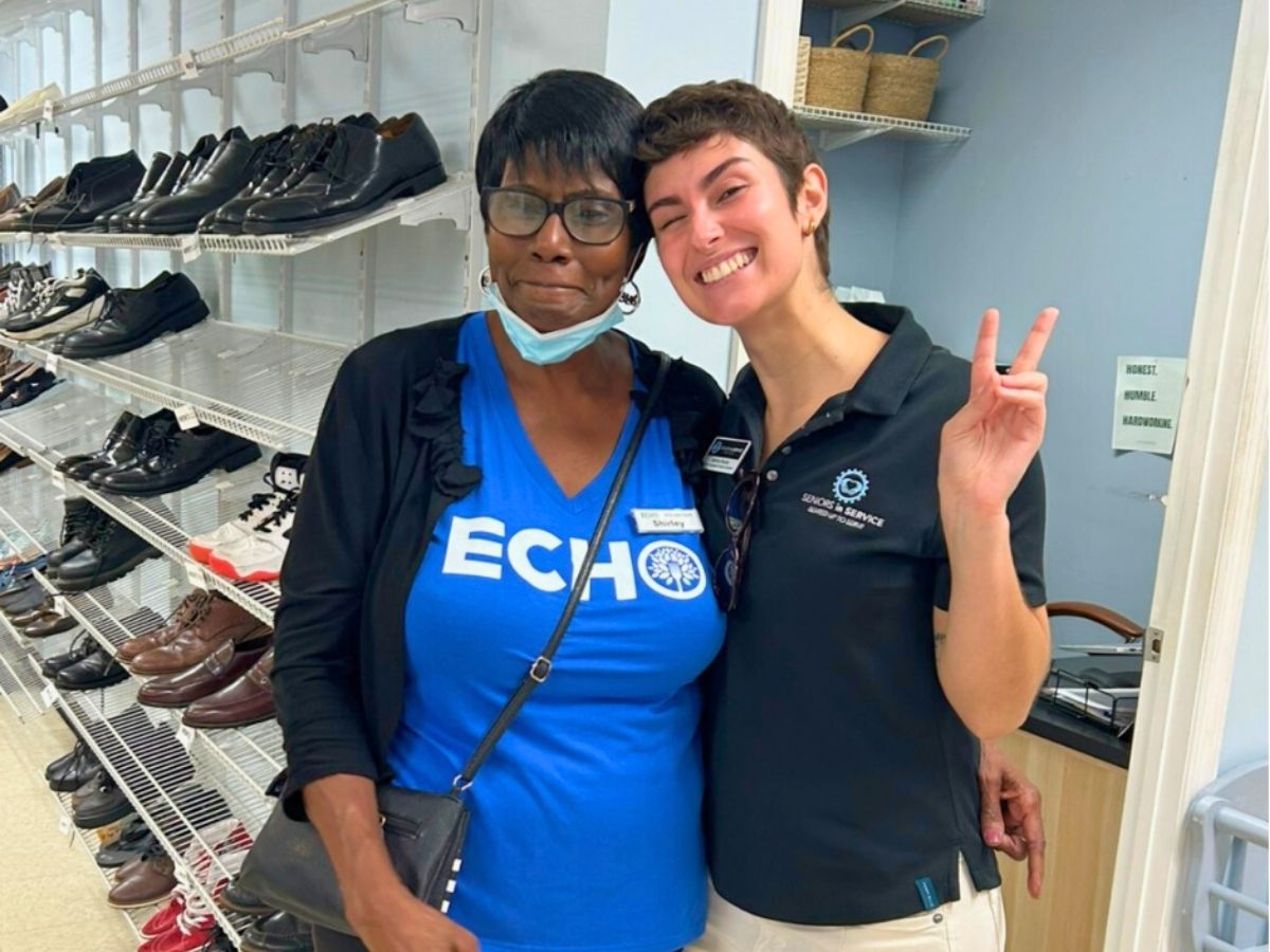 Shirley, a Seniors in Service volunteer, stands with a staff member at ECHO’s Resource Center in Brandon, helping families access clothing and essential resources.