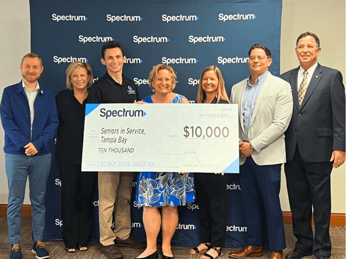 Seniors in Service staff members receive a Spectrum Digital Education presentation check for $10,000, accompanied by representatives from Spectrum and Hillsborough County.