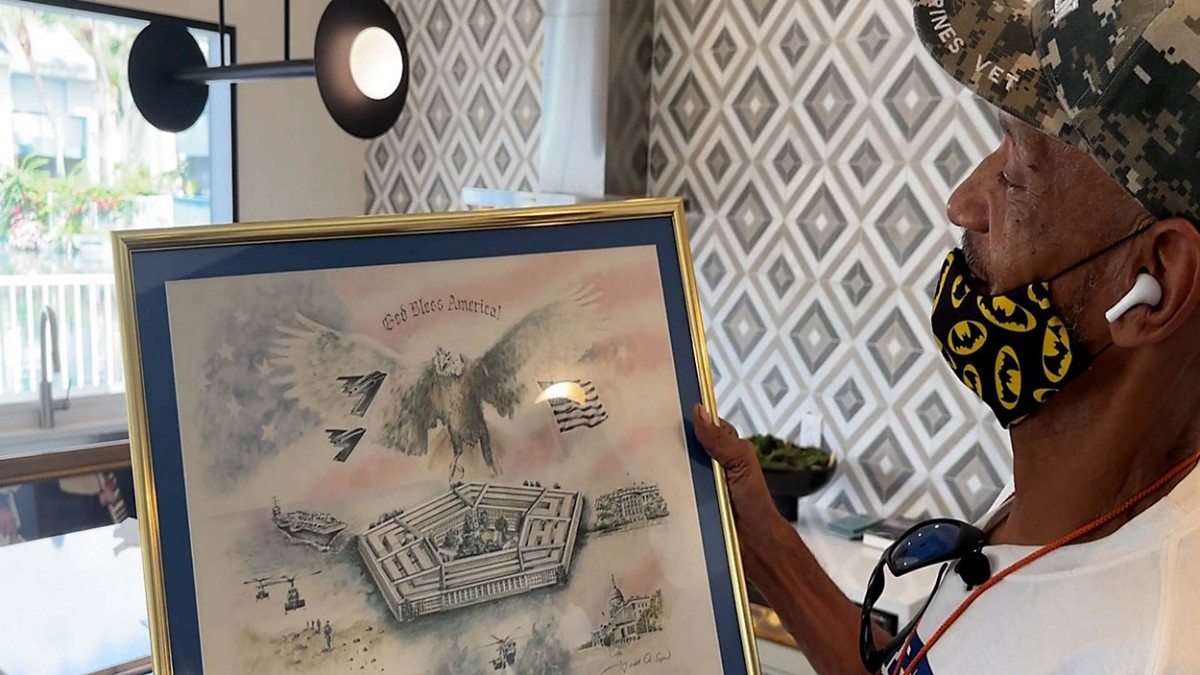 Veteran holding framed patriotic artwork during a Spectrum News feature story