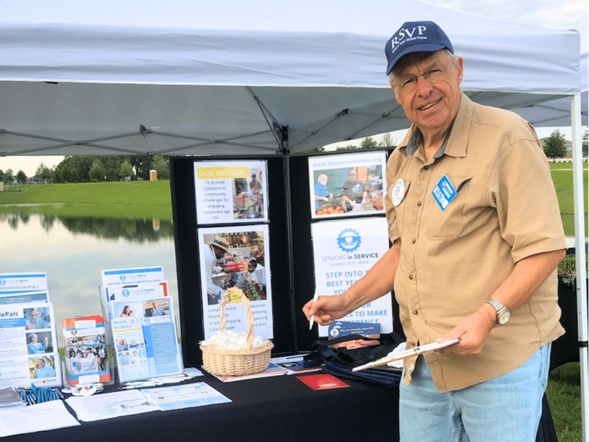 Volunteer Ambassador Vance Sheer welcomes community members at a Seniors in Service outreach event, encouraging adults 55 and older to volunteer.