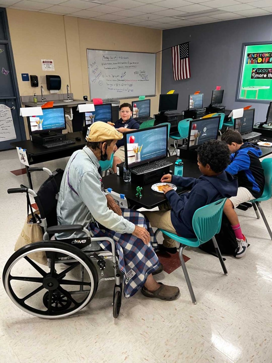 A Seniors in Service volunteer mentor meets with middle school students during a mentoring session at Ben Hill Middle School in Tampa.