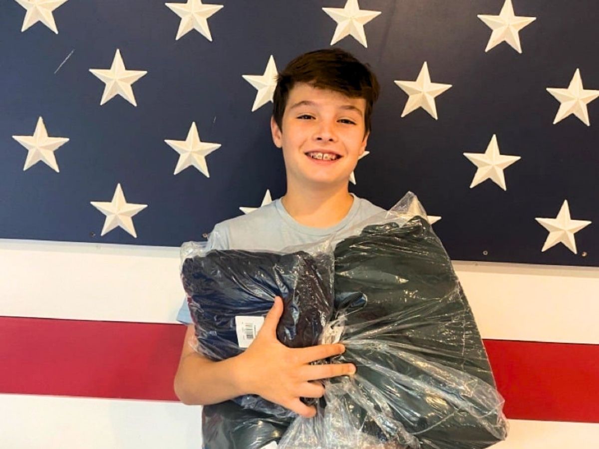 Young volunteer Grayson holds donated winter clothing for veterans during Operation: Veteran Connect&rsquo;s Warmth for the Winter Campaign.
